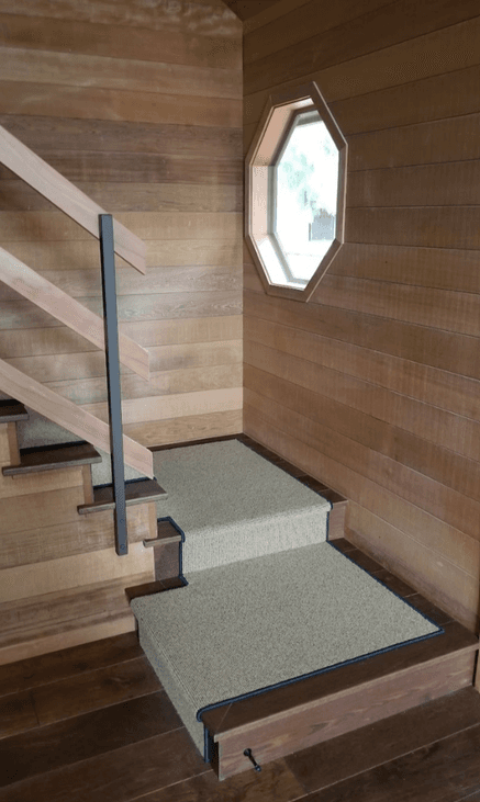Carpeted stair landing and treads with wood edging in a wood-paneled home